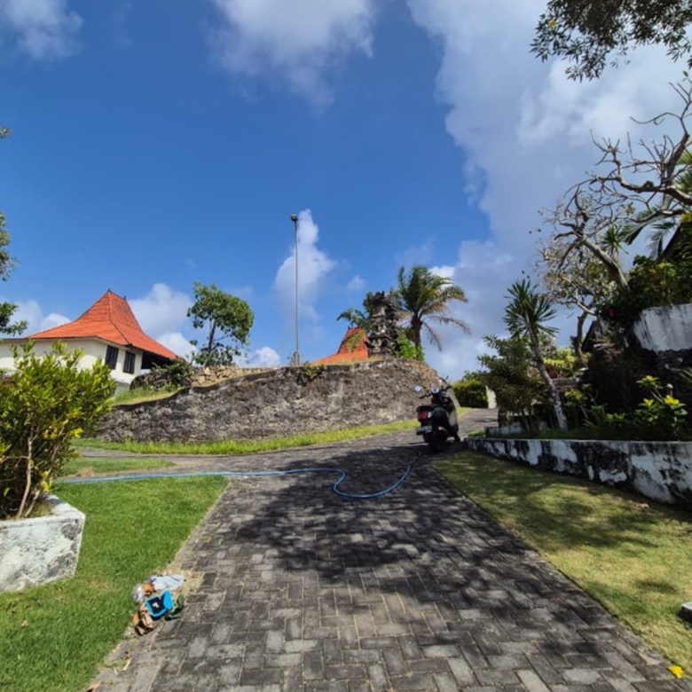 Melasti freehold plot, Bali: paved access road, stone retaining wall and Balinese-roofed pavilions