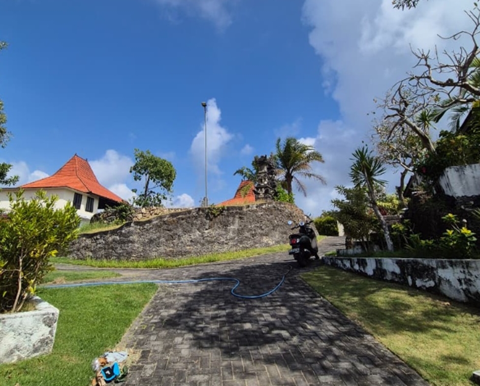 Melasti freehold plot, Bali: paved access road, stone retaining wall and Balinese-roofed pavilions
