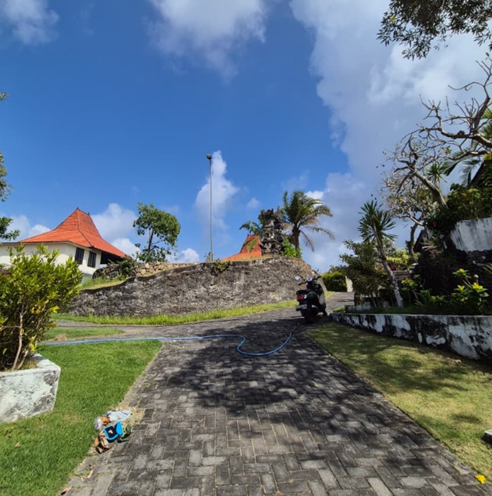 Melasti freehold plot, Bali: paved access road, stone retaining wall and Balinese-roofed pavilions